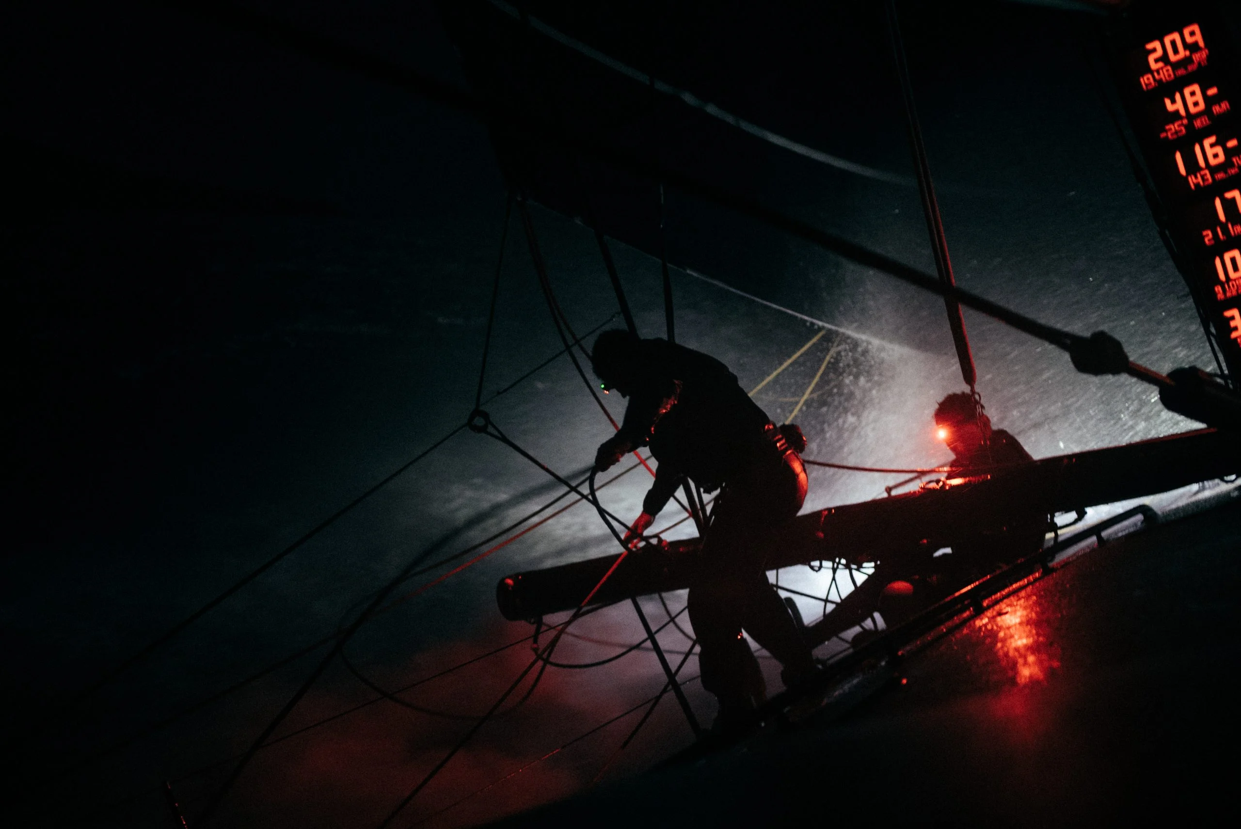 Crew working on deck at night, lit by the red instrument lights