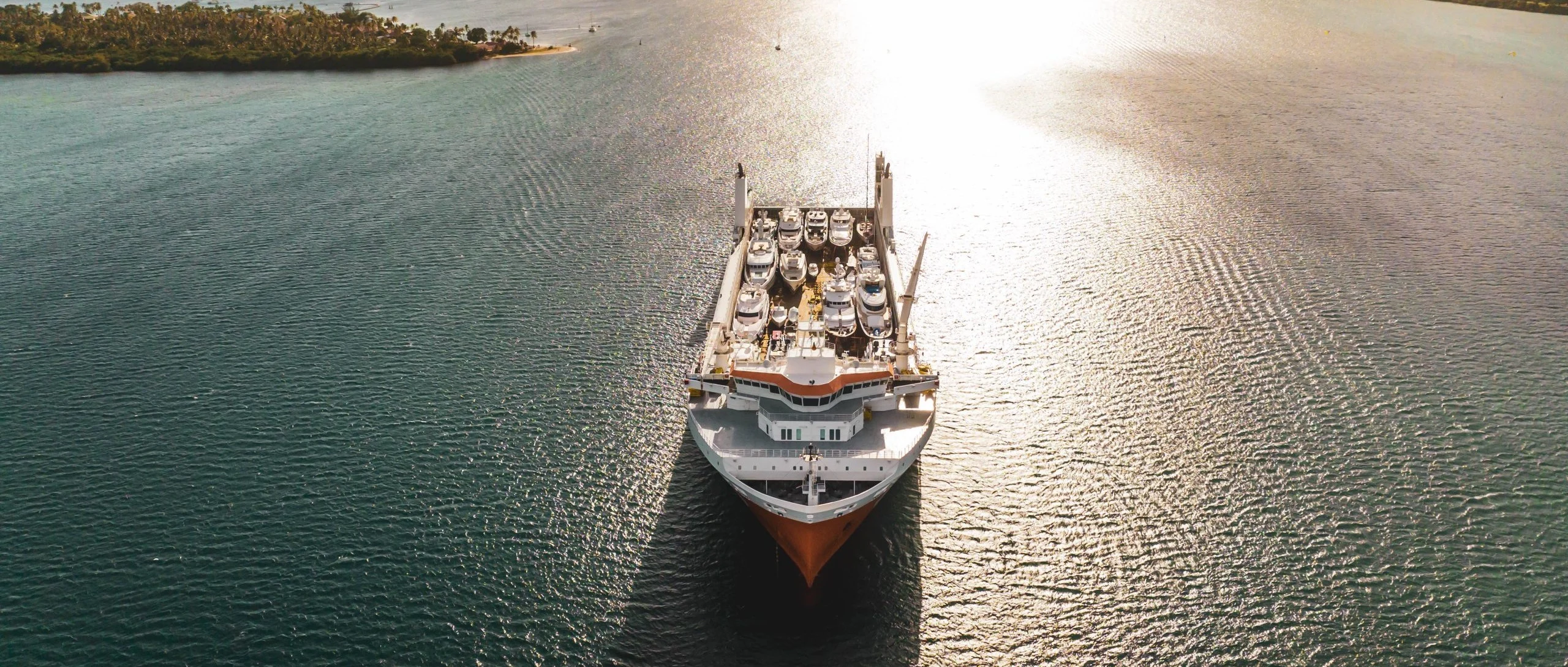 The loaded ship sailing out of a bay at sunrise