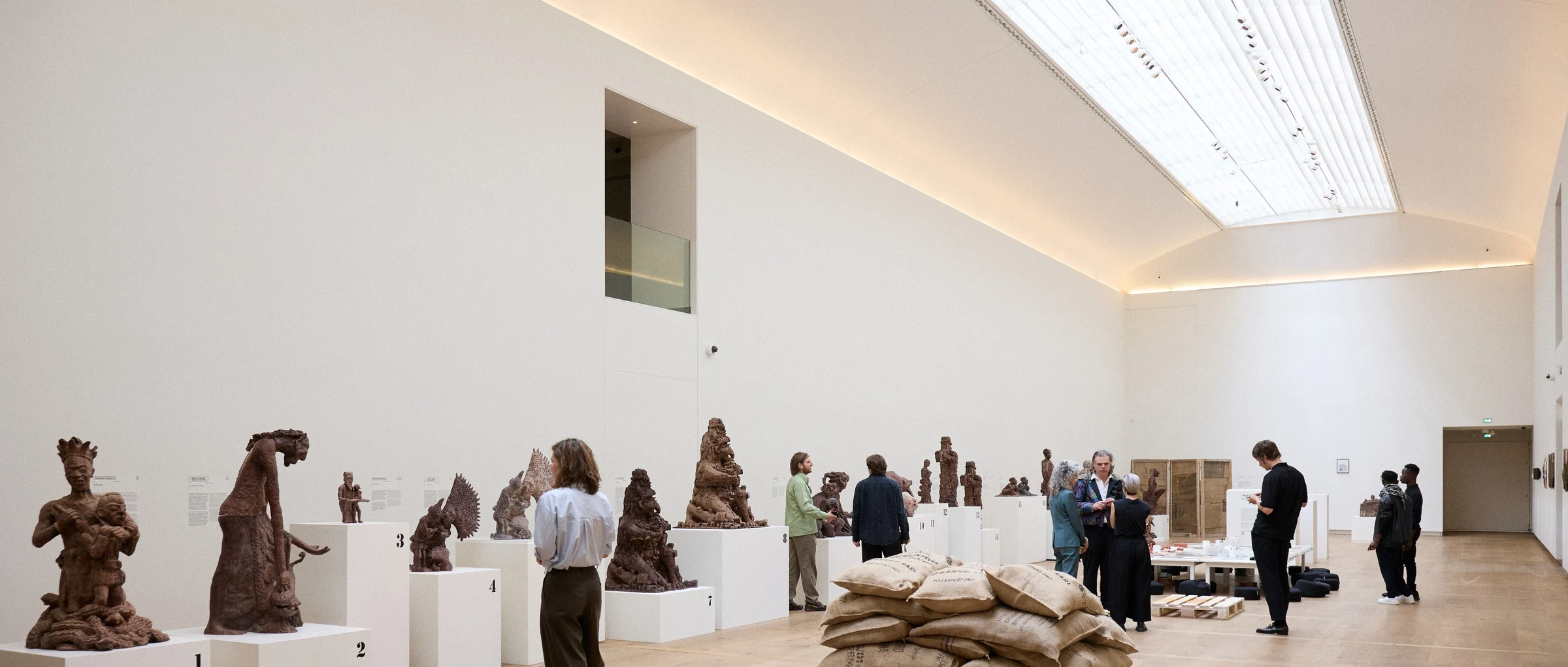 Visitors walk through a light museum gallery with sculptures on plinths