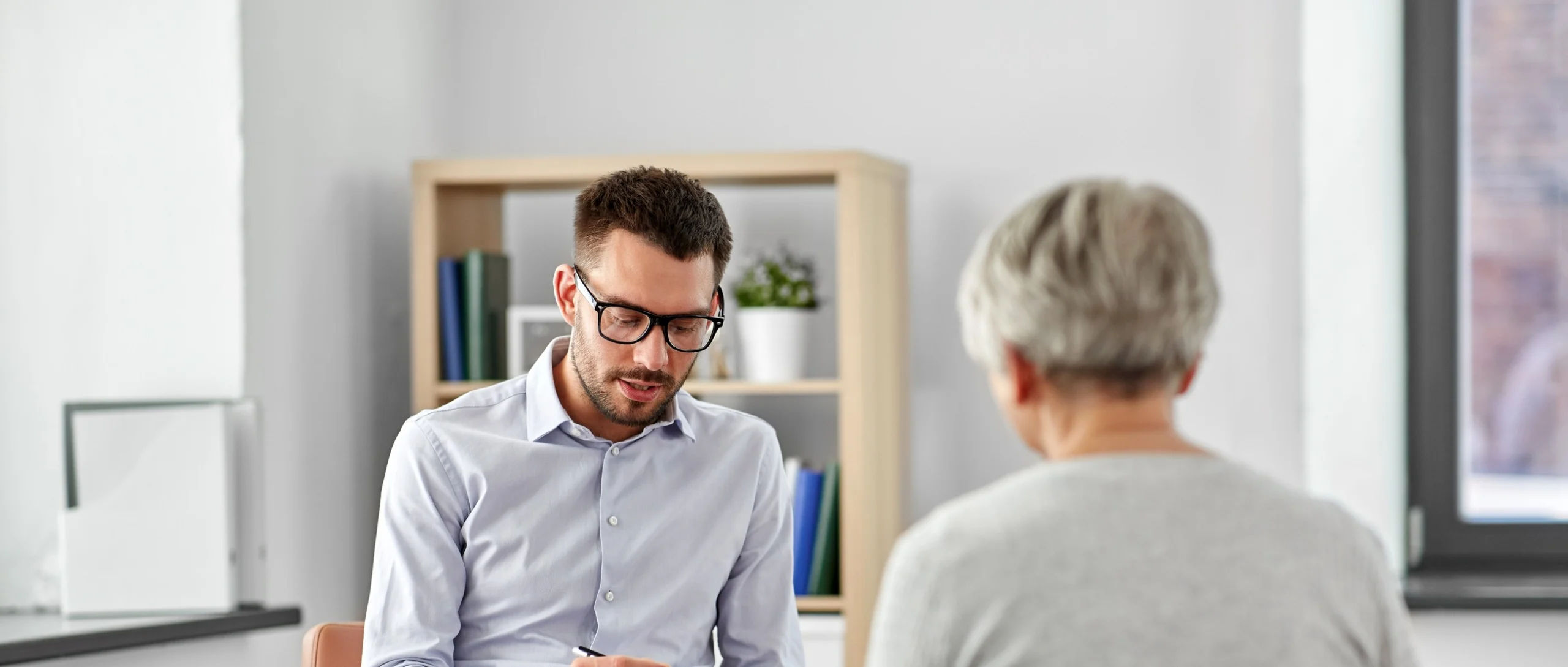 A legal specialist making notes during a conversation at a client's home