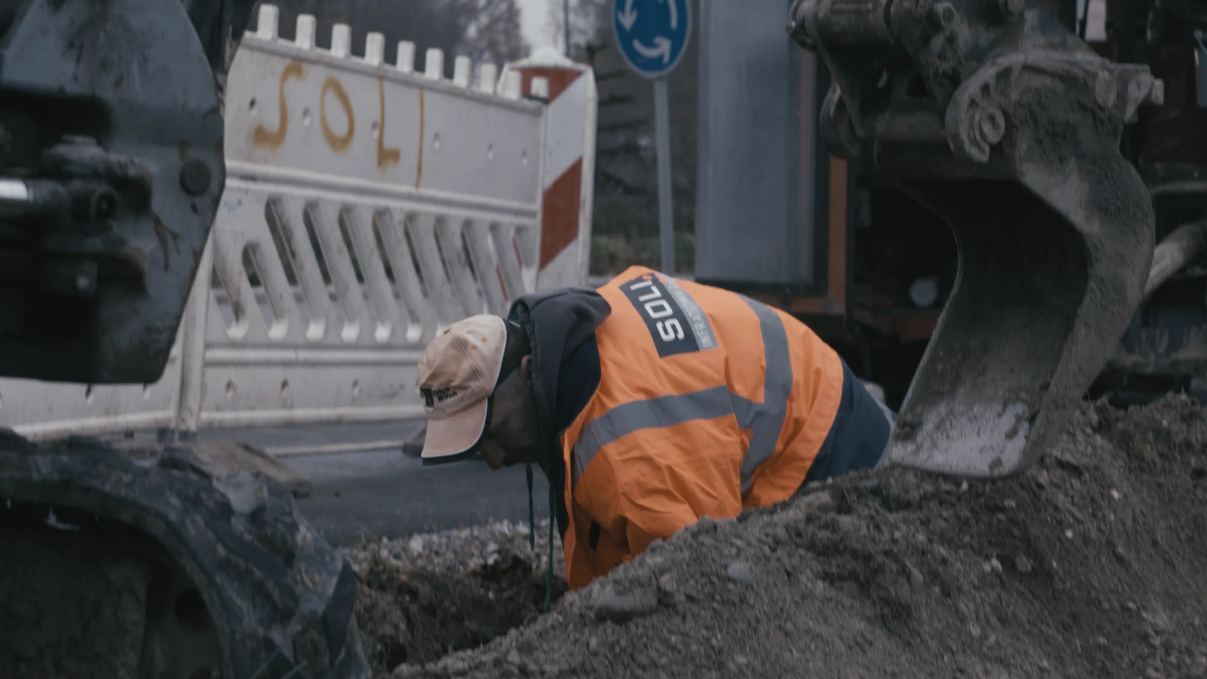 Field engineer working in an open trench beside a Soli road closure